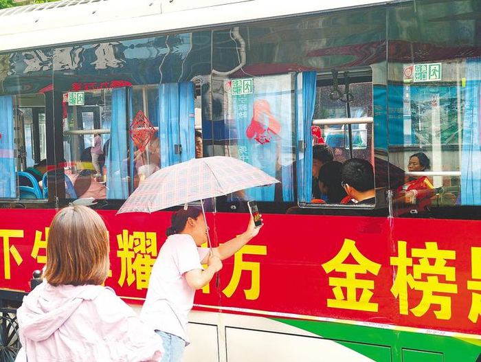 6月8日，襄阳一中高考考点外，一位送考的妈妈发现孩子坐在“金榜”上，特意拍下照片传递期许。（湖北日报全媒记者 赵恒 摄）