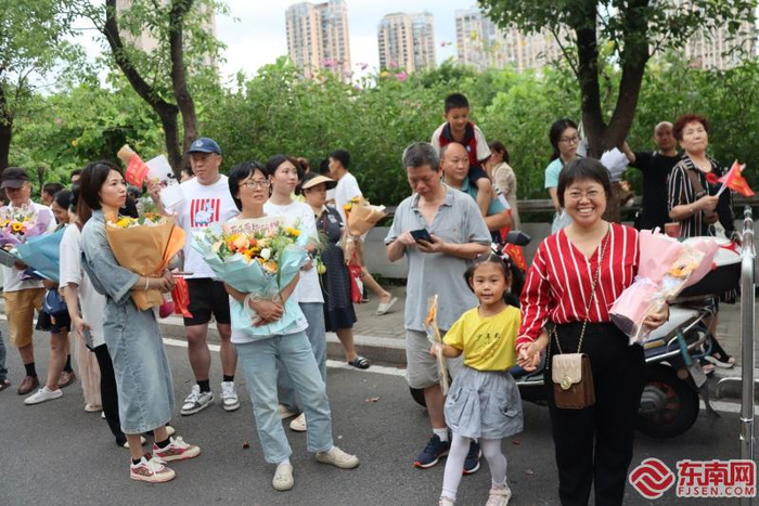 在福州七中考点外，学生家长手捧鲜花在等候。