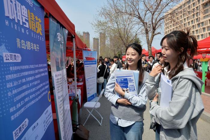 4月11日,学生在山东青岛科技大学2025年春季综合类大型双选会招聘活动现场查看企业资料。 新华社发(王海滨摄)