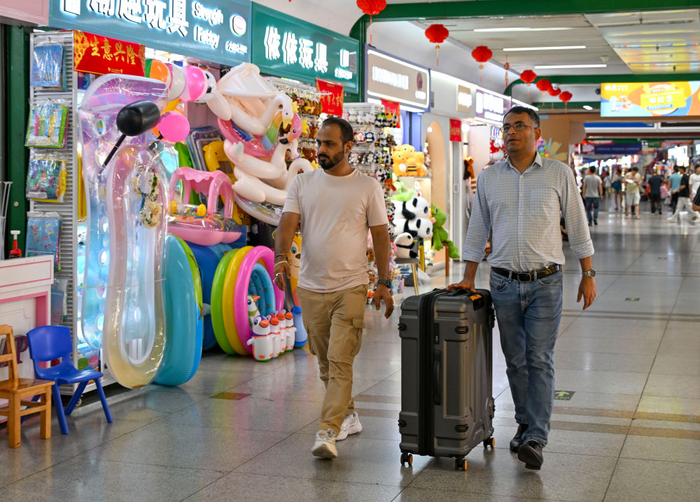 　　带着行李箱的外国客商在浙江义乌国际商贸城准备采购样品（5月16日摄）。新华社记者 陈朔 摄