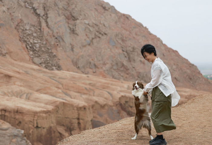 　　2025年5月4日，一名携带宠物的游客在位于新疆吐鲁番市鄯善县的吐峪沟大峡谷游玩。 新华社记者 王菲 摄