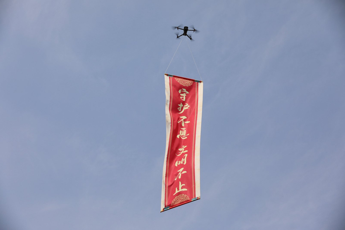 图为无人机悬挂“给未来文物寄语”卷轴腾空而起
