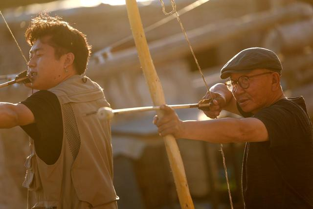 铁木尔加甫（右）在教一名游客练习射箭技艺（5月22日摄）。新华社记者 王菲 摄