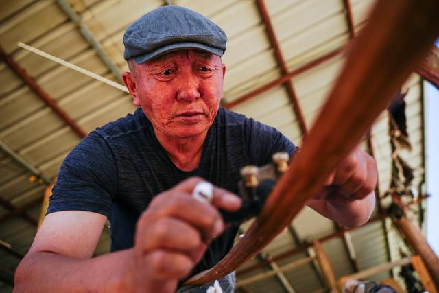 5月23日，在新疆阿勒泰市汗德尕特蒙古族乡汗德尕特村，铁木尔加甫制作弓箭。新华社记者 徐宏岩 摄
