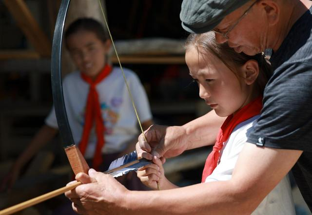 铁木尔加甫在自家院中给村里的小朋友教授射箭技艺（5月23日摄）。新华社记者 王菲 摄
