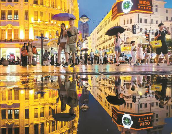             雨夜的南京路步行街商圈，游客与地面水中倒影融为一体  杨建正  摄          