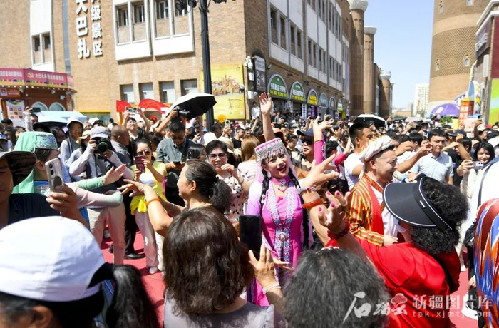 6月6日，游客在新疆国际大巴扎步行街与演员互动。石榴云/新疆日报记者 汤永摄