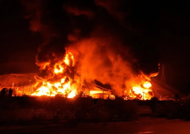 这是6月15日凌晨拍摄的伊朗首都德黑兰附近遭以色列袭击起火的储油设施。图源：新华社