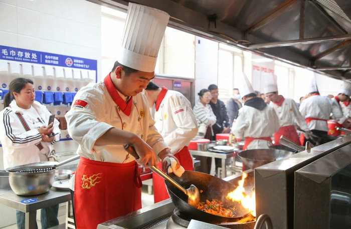 参加完求职能力实训营后，未继续升学高中毕业生郝熠军（左二）身着工装在岗位上实操（资料图片）。