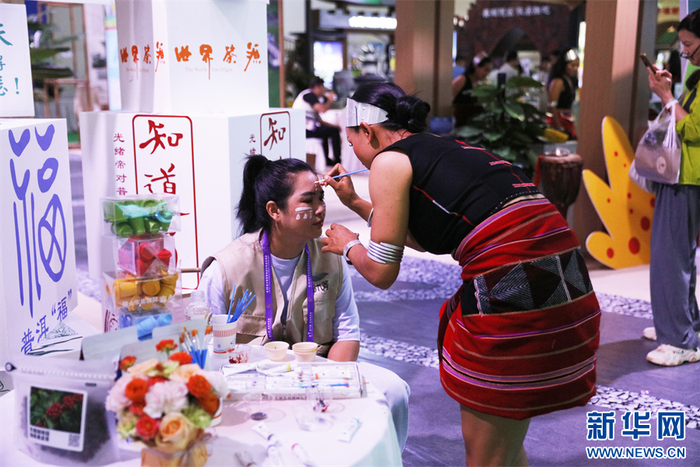 一位观众在普洱展区画上彩绘（6月20日摄）。新华网发（冯雨钐 摄）