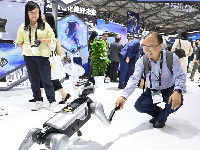 6月18日，观众在2025年世界移动通信大会（上海）中国电信展台与智能机器狗互动。记者　陈爱平　摄