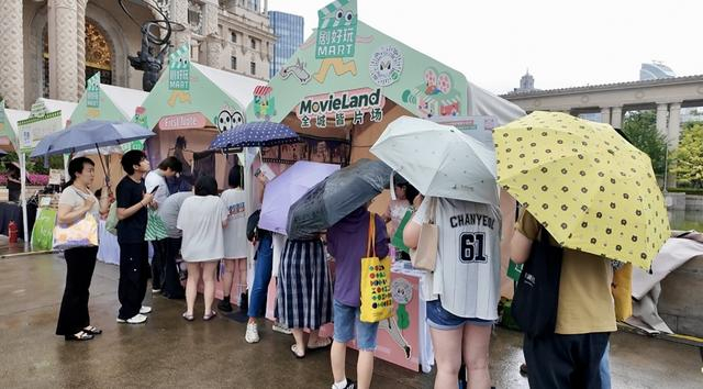 “剧好玩MART”市集里，Movie Land小程序摊位旁围聚着撑伞的影迷。（孙彦扬 摄）