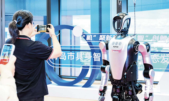 在2025青岛市具身智能机器人生态发展大会上，观众给乐聚夸父人形机器人拍照留影。