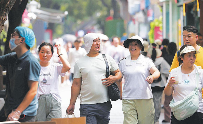 6月23日，南锣鼓巷，一位男士将湿毛巾顶在头上降温。　新京报记者　李木易　摄