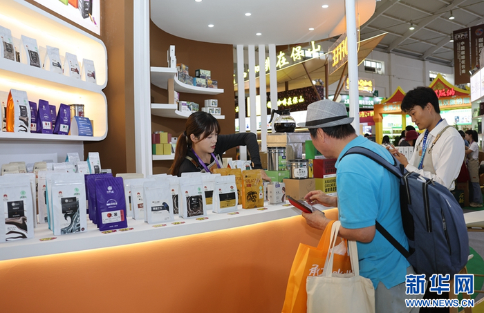 顾客在一家参展企业挑选云南咖啡（摄于6月19日）。新华网发（陈畅 摄）