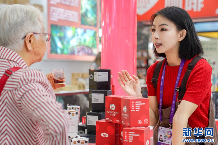 怒江展区的一名参展商（右）为顾客推介咖啡产品（摄于6月20日）。新华社发（彭奕凯 摄）