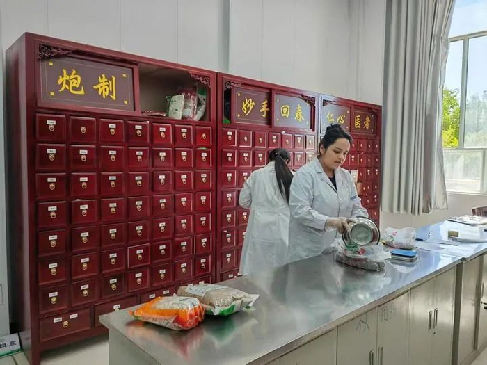 乌恰县人民医院中医药房的医师正在为患者取药