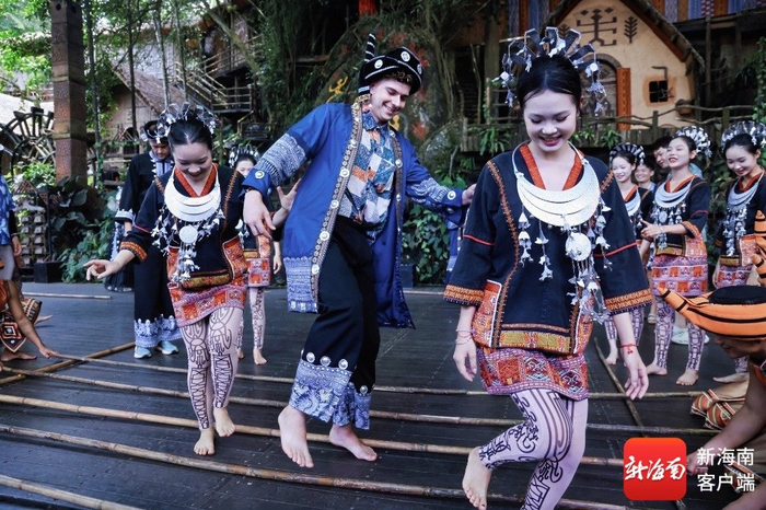 海南旅游国际推荐官在保亭槟榔谷黎苗文化旅游区和工作人员体验竹竿舞。主办方供图