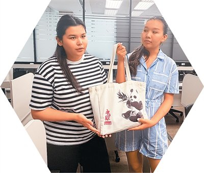 分校学生展示她们喜爱的有大熊猫元素的布包。本报记者 李贞摄