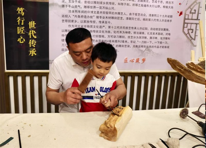 日前，许红阳教儿子雕刻木雕作品。 省文明办供图