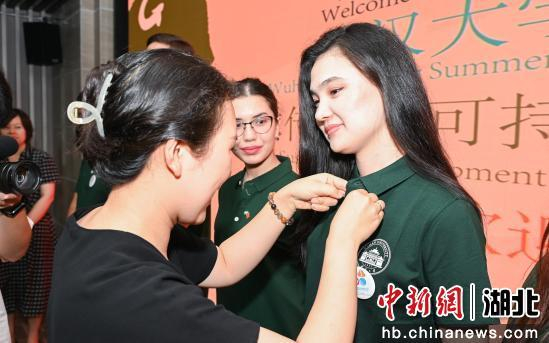 志愿者和中外教师、专家代表共同为暑期学校的新生代“文化使者”佩戴纪念徽章。湖北画报国传中心供图