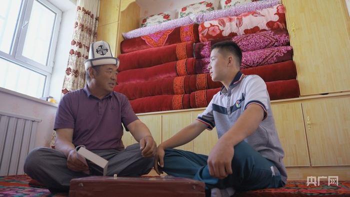 耶提库与儿子玉米塔力一起读《玛纳斯》（央广网记者  顾炀威  摄）