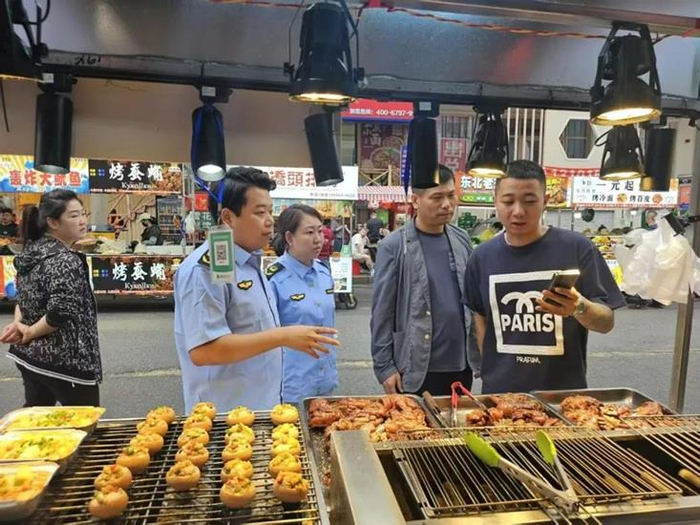 执法人员向摊主和市民讲解食品选购、储存、加工注意事项。资料图片