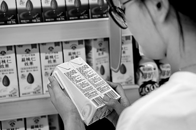     浙江台州路桥区螺洋街道一超市内，顾客比对配料表挑选食品。胡康优摄/光明图片