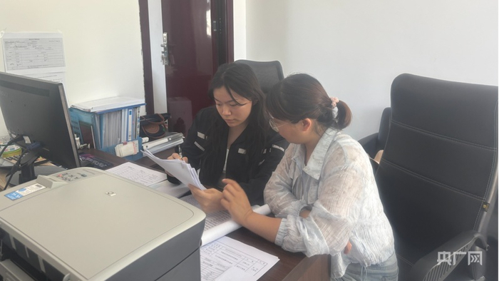 朱一然（左一）帮同事整理材料（央广网发  受访者供图）