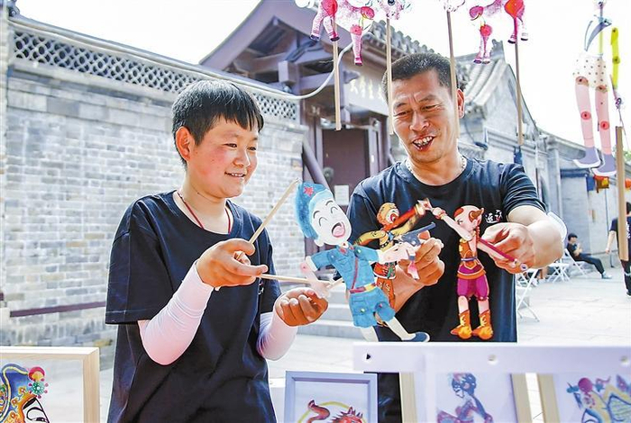     王永跃（左）展示皮影