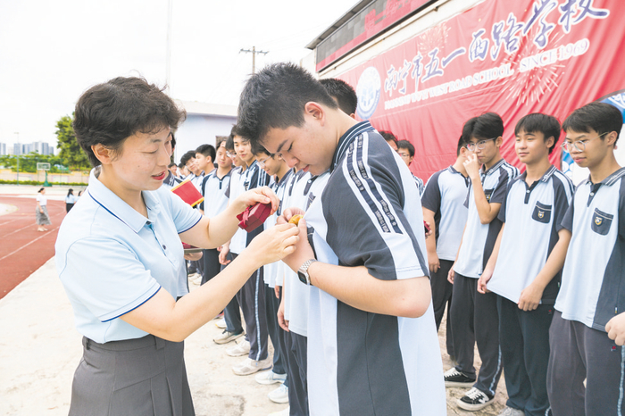     ◀南宁市五一西路学校校长为九年级学生佩戴专属毕业徽章。本报通讯员陈淑贤 摄