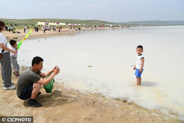 ↑2025年6月28日，游客在内蒙古锡林郭勒盟太仆寺旗白音查干湖边拍照打卡。CICPHOTO/孙慧军 摄