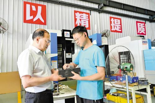     6月25日，霸州市信安镇仁义街党支部书记刘树马（左）在宏伟机械有限公司检查机械部件产品质量。 本报记者 王 伟摄