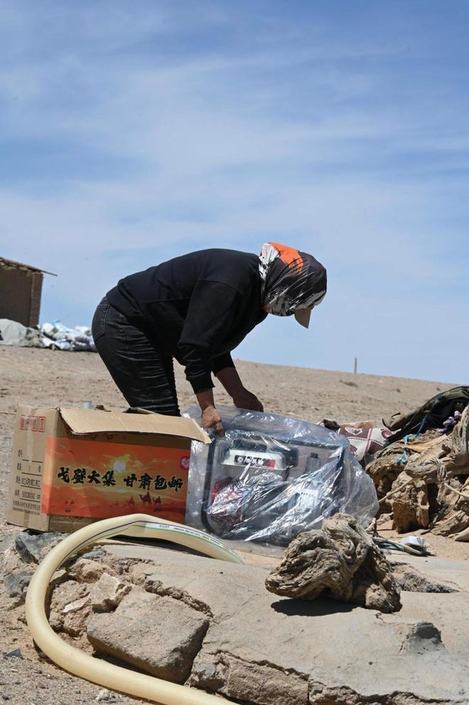 ▲孟根正拆开从拼多多上网购回来的发电机。陈蕾｜摄