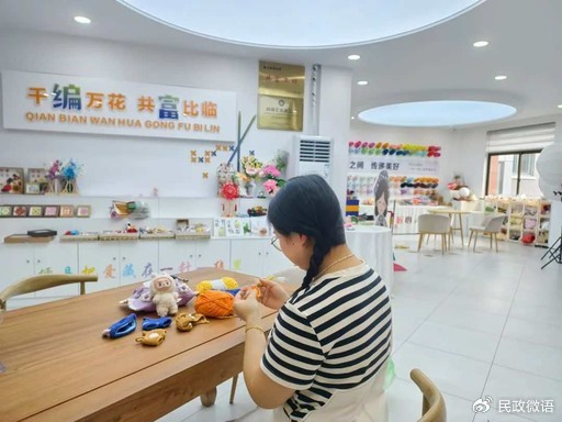 梅如雪正在共富工坊里制作娃衣。张华颖 摄