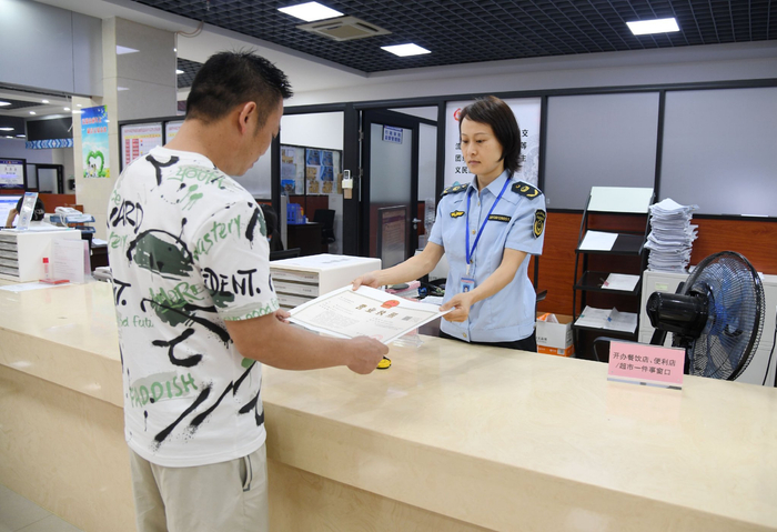 来宾市兴宾区市场监管局服务窗口工作人员向转型升级为公司有关负责人颁发《营业执照》