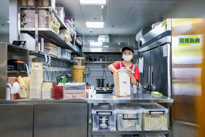 图为“浣熊食堂”的店员完成餐品制作后正在打包封签，这些动作都在明厨亮灶直播状态下完成。 王天壮摄