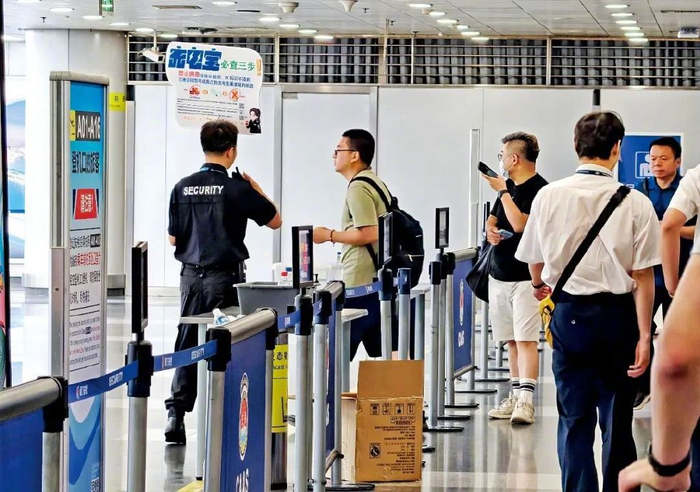 6月28日，北京首都国际机场安检区域，工作人员提示旅客检查充电宝。图/视觉中国