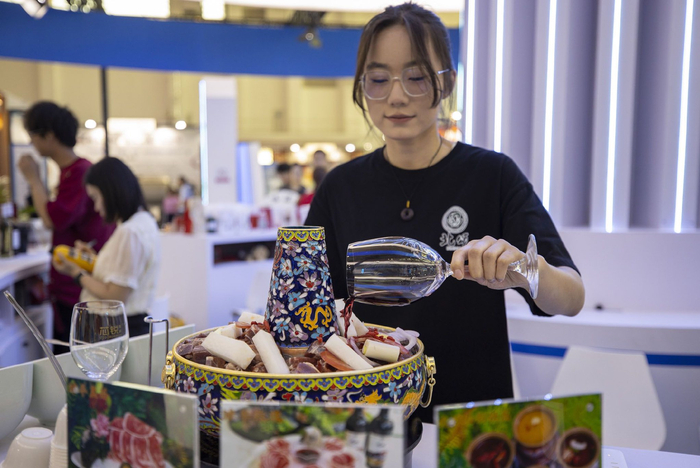 近日，在第五届中国（宁夏）国际葡萄酒文化旅游博览会上，一家参展商的工作人员在烹饪红酒涮肉。新华社记者　杨植森　摄