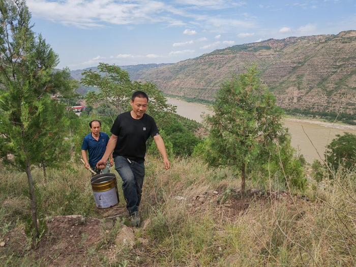 6月18日，郝雷（前）与队长王永红提水上山。新华社记者 孙正好 摄
