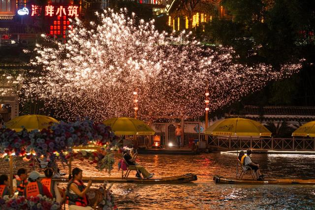 7月9日，游客乘坐“龙游贡水”竹筏在贡水河上观赏打铁花表演。新华社记者 伍志尊 摄