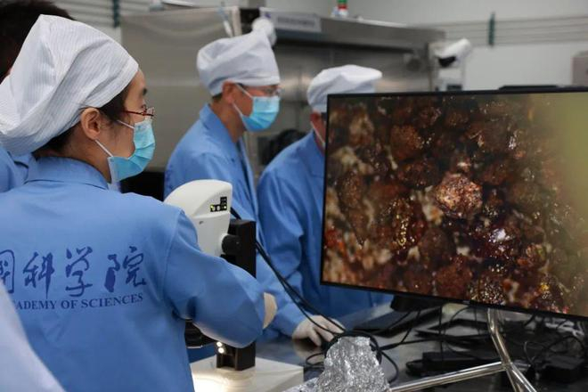 国家天文台科研人员查看岩屑显微镜成像照片。图片来源：中国科学院
