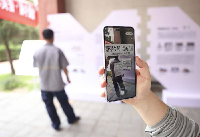 居民用手机扫描展板上的专属二维码，便可再现玲珑塔等十余个历史场景，让沉睡的文物在指尖“活”了起来。新京报记者 浦峰 摄