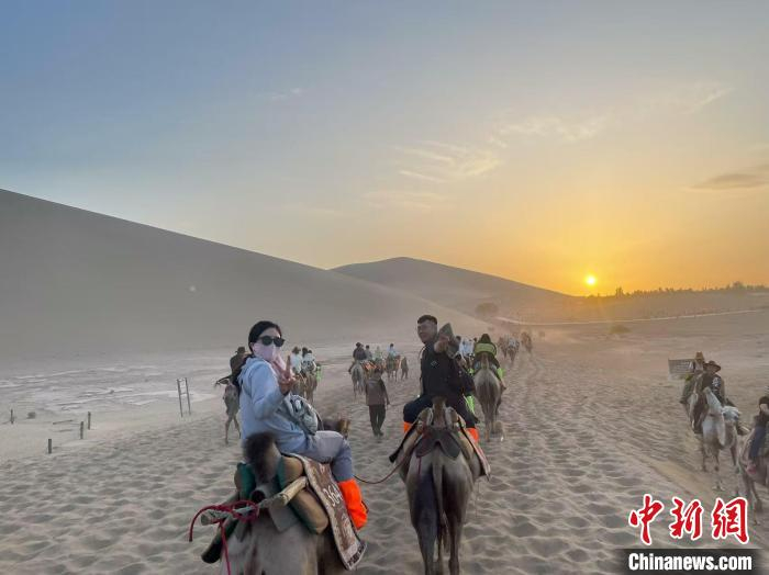 图为台胞青年在鸣沙山月牙泉景区骑骆驼。申志波 摄