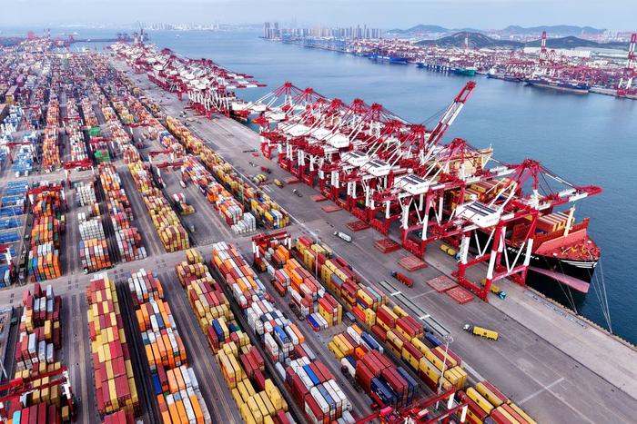 　　  5月5日，在山东港口青岛港，货轮在装卸外贸集装箱（无人机照片）。新华社发（俞方平 摄）