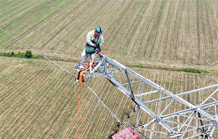近日，在安徽省亳州市利辛县程家集镇，电力工人正在对辖区220千伏输电线路进行带电检修。　图片来源：视觉中国
