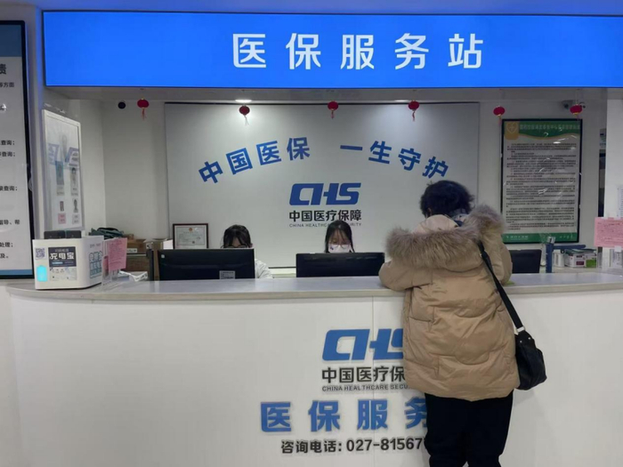 图说：武汉一家药店内，患者在医保服务站咨询摄/辛颖