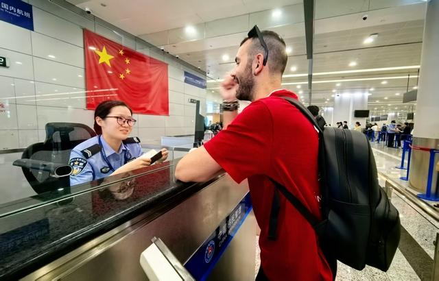 在浦东国际机场口岸，移民管理警察为旅客办理边检查验手续（魏文亨 摄）
