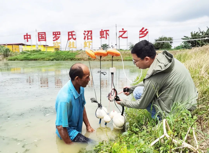 △高要区气象局工作人员为虾农讲解水体监测设备。肇庆市融媒体中心记者 潘粤华 摄