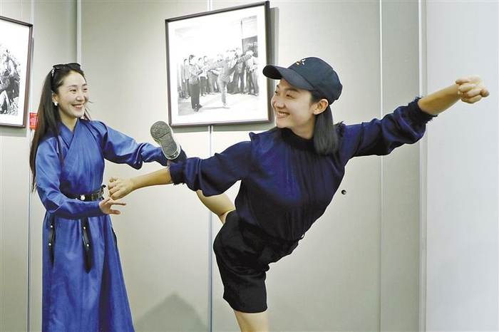 新一代乌兰牧骑队员模仿照片中老一代队员的舞蹈动作。郭成 摄